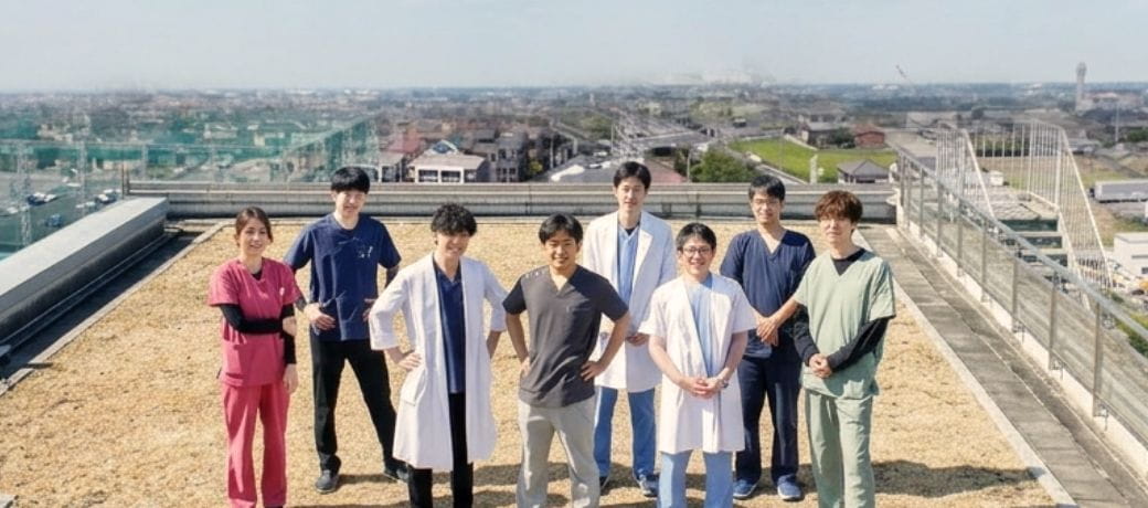 病院の屋上に並ぶイムス埼玉越谷病院の医師・看護師・リハビリスタッフ