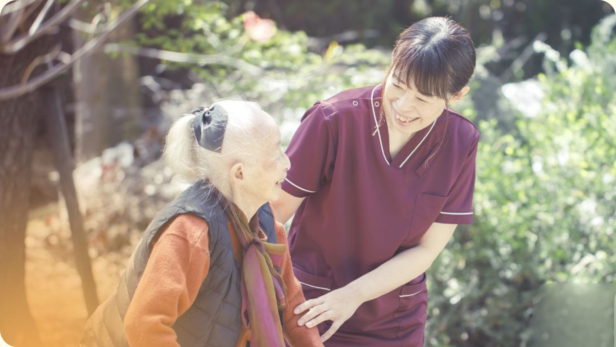 庭先で高齢の患者さまに寄り添い笑顔で語りかける当院の看護師