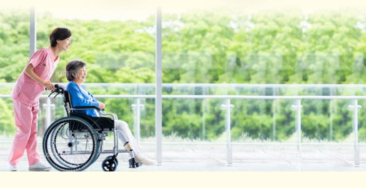 車椅子の患者さまを介助しながら渡り廊下を歩く看護師